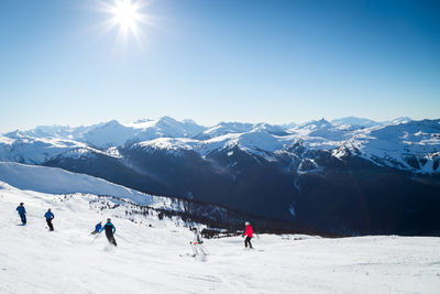 People skiing on snowcapped mountain against sky