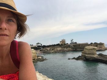 Portrait of young woman looking at sea against sky