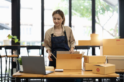 Side view of young woman using laptop at home