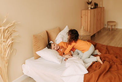 Funny happy kids brother and sister in pajamas playing having fun in a cozy bedroom at home