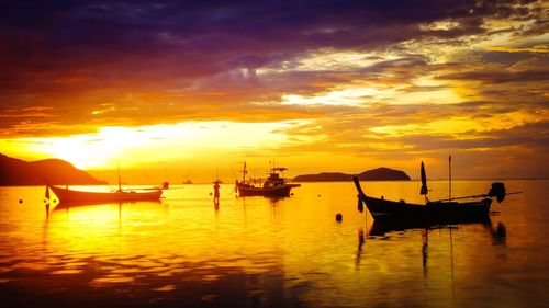 Silhouette boats in sea against sky during sunset