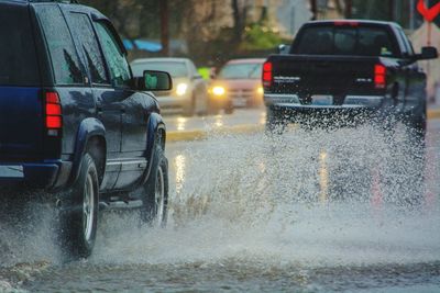 Cars splashing water on road in rainy season