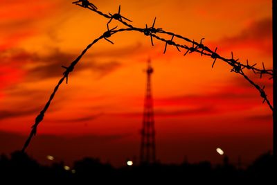 Close-up of silhouette barbed wire against sky during sunset