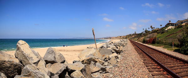 Panoramic view of railroad tracks by sea against sky