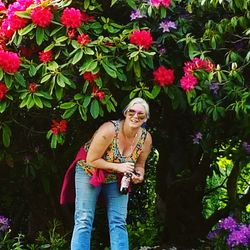 Portrait of young woman standing against pink flowers