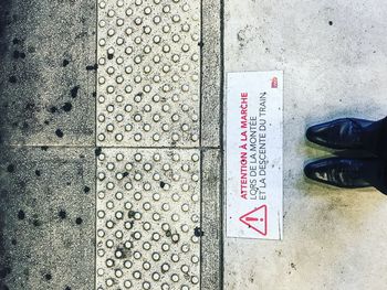 Low section of man standing by text on floor