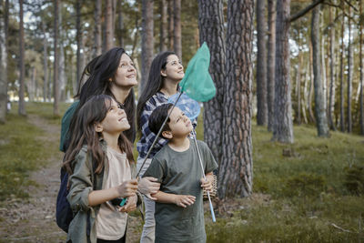 Women standing on tree trunk in forest