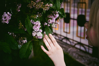 Close-up of young woman touching butterfly on flowers