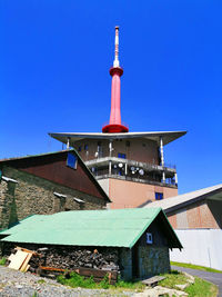 Lighthouse by building against clear blue sky