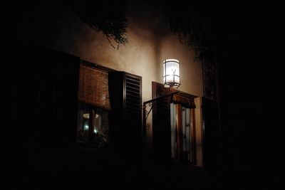 Low angle view of illuminated street light against building at night