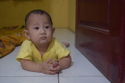 Portrait of cute baby boy lying on floor