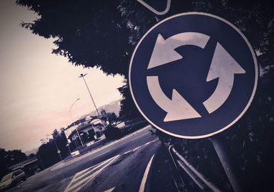 Road sign on street against sky