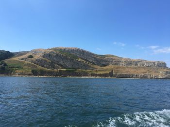 Scenic view of sea and mountains against clear blue sky