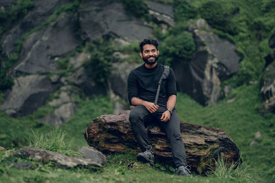 Young man sitting on rock