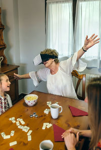 Granddaughter looking at grandmother wearing virtual reality simulator