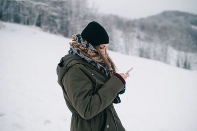 Woman using mobile phone on snow covered landscape
