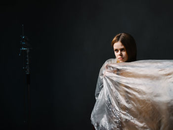 Portrait of young woman over black background