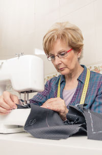 Senior woman using sewing machine at workshop