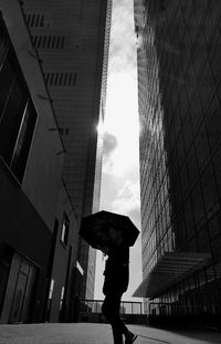 Low angle view of woman on street amidst buildings against sky