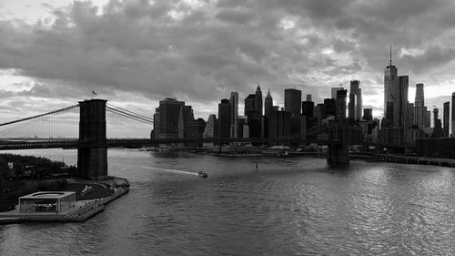 Modern buildings by river against sky in city