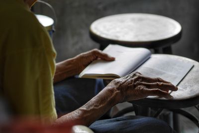 Midsection of person reading book while sitting on table