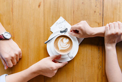 Midsection of woman holding coffee cup on table