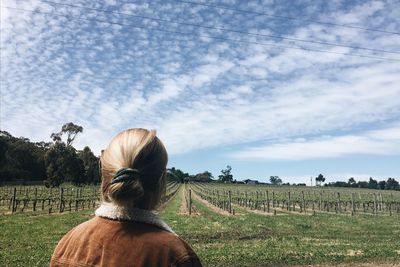 Rear view of woman in field against sky