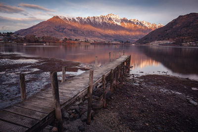 Scenic view of lake by mountains against sky during sunset