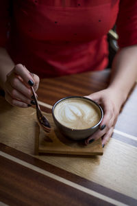 Midsection of woman holding coffee cup on table