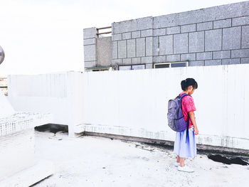 Woman standing by building against wall
