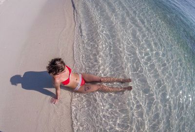 High angle view of woman in bikini sitting on shore