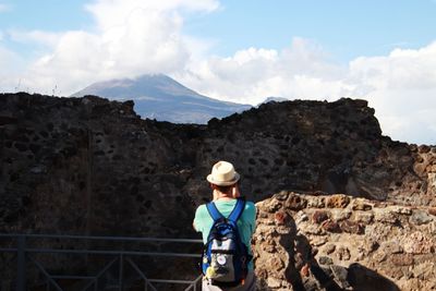 Man standing on rock against sky