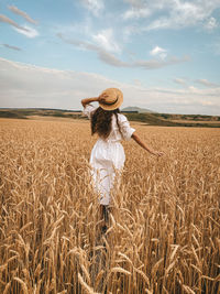 Woman wearing hat on field against sky