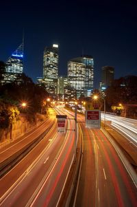 Light trails on road amidst buildings in city at night