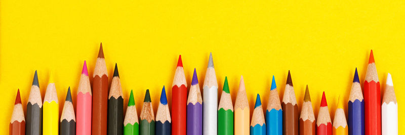 Close-up of colored pencils against yellow background