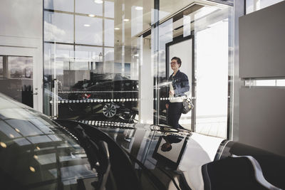 Senior woman seen through glass entering in car showroom