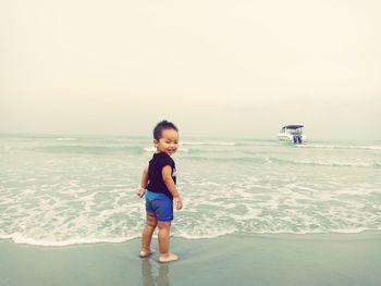 Full length of boy on beach against sky