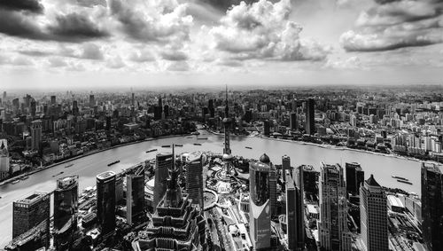 High angle view of city buildings against cloudy sky