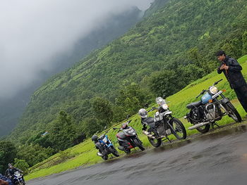 People riding motorcycle on road against mountains