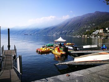 Boats sailing on river by mountains against sky