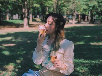 Young woman eating ice cream while sitting outdoors