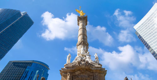 Low angle view of statue by buildings against sky