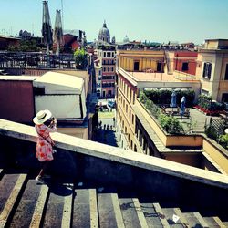 Rear view of woman standing by buildings against clear sky