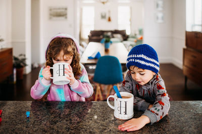 Young boy and girl drinking hot chocolate inside on a cold winter day