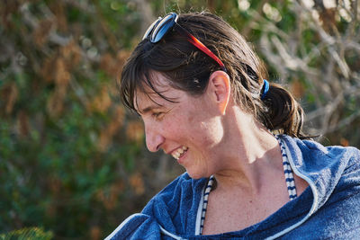 Woman with sunglasses in her hair and blue towel in a pool looks down