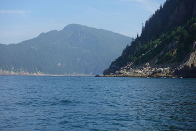 Scenic view of sea by mountains against sky