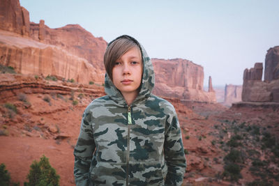 Portrait of man standing against rock formation