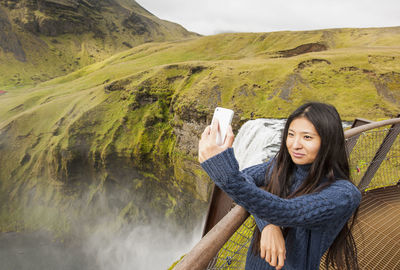 Beautiful woman taking selfie at skogarfoss waterfall in iceland