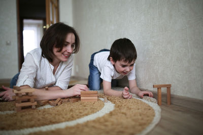 Happy family. mother and son playing in wooden designer and smiling. little boy having fun with 