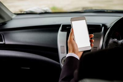 Cropped image of businessman holding smart phone while sitting in car